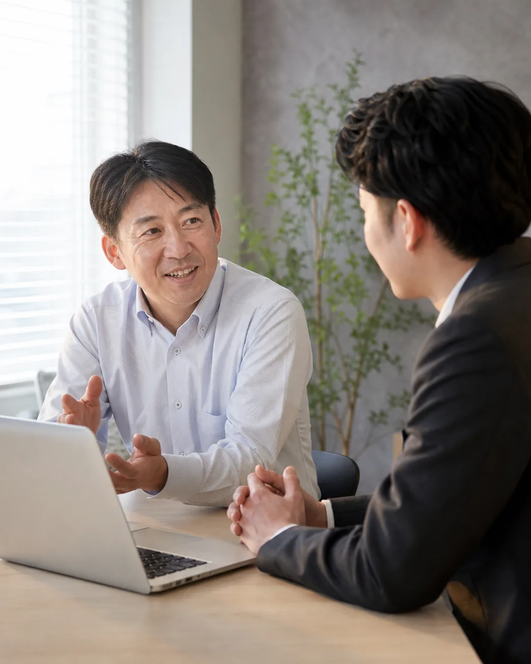 ミーティングテーブルで会話する日本人ビジネスマン2名